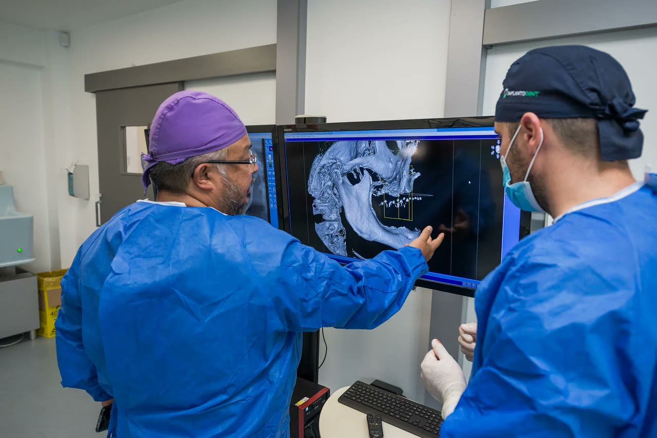 Doi medici Implantodent analizează reconstrucția 3D a maxilarului pentru planificarea digitală a implanturilor