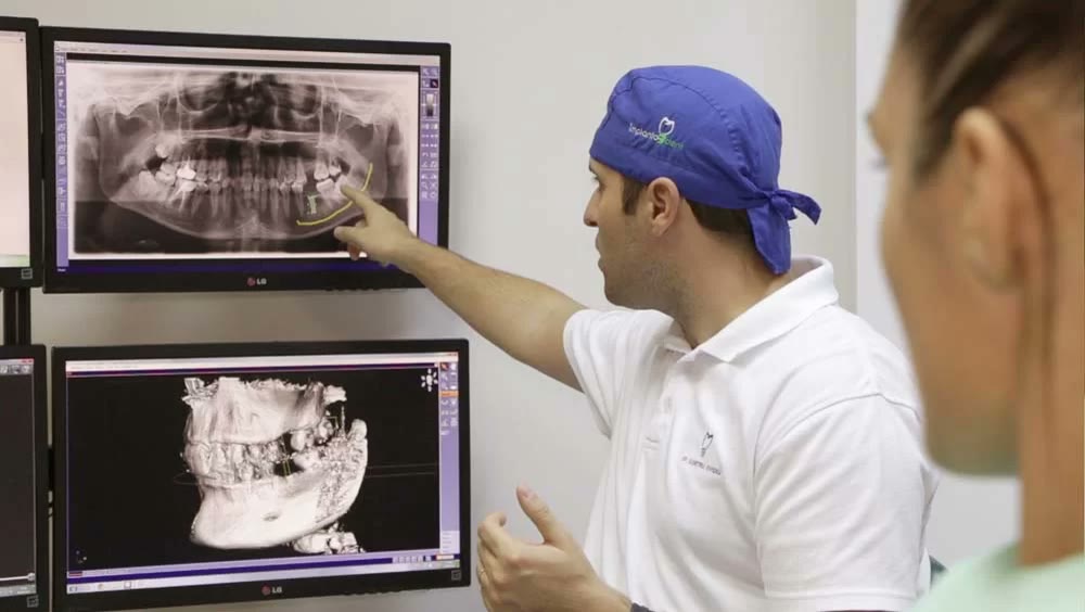 Medic implantolog explică pacientei radiografia panoramică și reconstrucția 3D obținută prin tomografie dentară